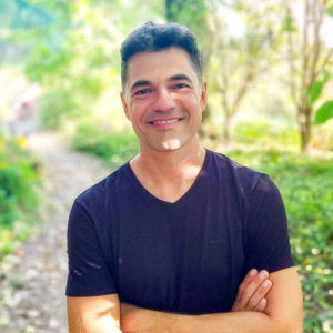 Akram El-Bahay, Foto: Julia Reibel-El-Bahay Lächelnder Mann mit dunklem T-Shirt, steht in einer grünen Umgebung beim Elbenwald Festival. Die natürliche Kulisse und die entspannte Atmosphäre spiegeln die Verbindung von Musik und Nerdkultur wider.