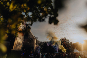 100 Kilo Herz Buntes Treiben beim Elbenwald Festival: Livemusik, feiernde Menschen und spektakuläre Effekte unter dem Abendhimmel. Die Bühne ist beleuchtet, während bunte Rauchwolken und Konfetti die festliche Atmosphäre unterstreichen.