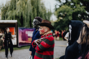 Cosplay von ikonischen Horrorfiguren beim Elbenwald Festival. Zu sehen sind Charaktere mit markanten Masken und Kostümen, die die lebendige Atmosphäre des Festivals widerspiegeln. Besucher genießen die Mischung aus Musik und Nerdkultur in einer bunten Umgebung.
