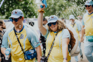 Zwei Festivalbesucher in bunten Outfits mit Pokémon-Motiven, die Wasserpistolen halten und von Seifenblasen umgeben sind. Die fröhliche Atmosphäre spiegelt die kreative und verspielte Stimmung des Elbenwald Festivals wider.