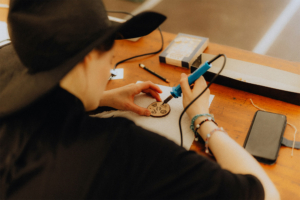 Creative Hobby Workshop Eine Person arbeitet am Elbenwald Festival mit einem Lötkolben an einem Holzstück, um eine detaillierte Gravur zu erstellen. Auf dem Tisch sind Werkzeuge und Materialien verteilt, während die kreative Atmosphäre des Festivals spürbar ist.