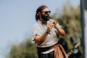 Katerfahrt live Ein Musiker im Piratenkostüm spielt eine Flöte auf dem Elbenwald Festival. Die Szene zeigt die lebendige Atmosphäre des Festivals, das Musik und Nerd-Kultur vereint, unter blauem Himmel und umgeben von Bäumen.