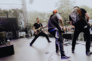 Kontrollverlust Live-Auftritt auf dem Elbenwald Festival, Musiker auf der Bühne mit E-Gitarre und Bass, begeisterte Menge im Hintergrund, kreative Atmosphäre, Mischung aus Musik und Nerd-Kultur, unvergessliche Festivalerfahrung.