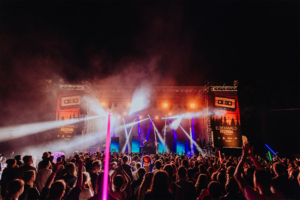 Nerds at Raves live Bunte Lichter und eine begeisterte Menge beim Elbenwald Festival. Die Bühne ist von Nebel umgeben, während Künstler auftrumpfen und die Fans mit leuchtenden Stäben feiern. Ein unvergessliches Erlebnis für Musik- und Fantasy-Liebhaber.