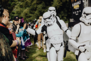 501st Legion Cosplay von Stormtroopern beim Elbenwald Festival, wo Fans in bunten Kostümen mit den Charakteren interagieren. Die Atmosphäre ist lebhaft, während die Teilnehmer die Mischung aus Musik und Nerdkultur genießen.