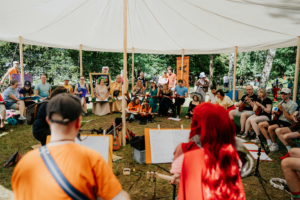Ukulele mit Bina Bianca Teilnehmer des Elbenwald Festivals versammeln sich in einem Zelt, um gemeinsam Musik zu machen. Die bunten Kostüme, Instrumente und die entspannte Atmosphäre schaffen eine kreative und inspirierende Umgebung für Fans von Popkultur und Musik.