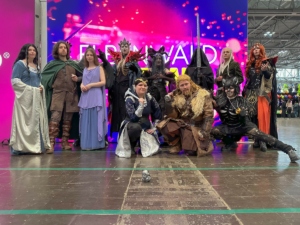 Gruppe von Cosplayern in fantasievollen Kostümen auf dem Elbenwald Festival, umgeben von bunten Lichtern. Die Teilnehmer präsentieren eine Mischung aus klassischen und modernen Charakteren, die die kreative Atmosphäre des Events widerspiegeln.